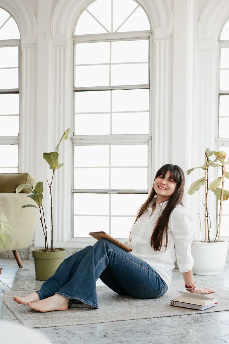 Tania Brambila sentada en su espacio de trabajo con libros